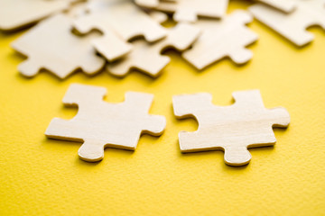 Wooden puzzles on a yellow background, close-up, soft focus