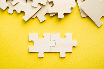 Fototapeta premium Wooden puzzles on a yellow background, close-up, soft focus