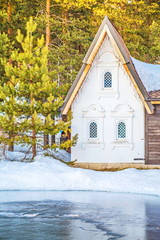 Little fabulous white house in  winter forest on  shore of  frozen lake