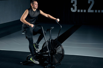 Fototapeta na wymiar Fitness male using air bike for cardio workout at Functional training gym.
