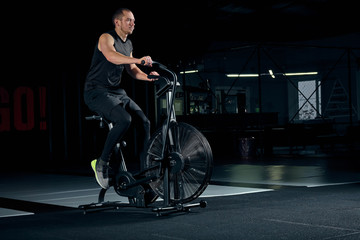 Obraz na płótnie Canvas Male using air bike for cardio workout at cross training gym.