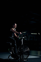 Fototapeta na wymiar Male using air bike for cardio workout at cross training gym.