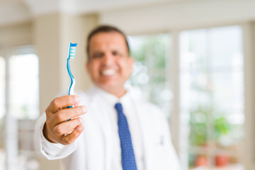 Middle age dentist man holding toothbrush and smiling