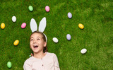 Laughing girl with colored eggs in meadow