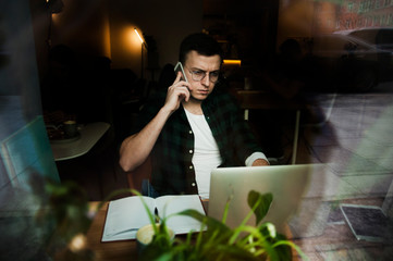 A guy in a cafe with a laptop working in a cozy place with a cup of coffee, gets pleasure. The concept of work in pleasure