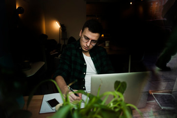 A guy in a cafe with a laptop working in a cozy place with a cup of coffee, gets pleasure. The concept of work in pleasure