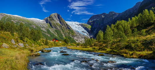 Norwegian landscape with milky blue glacier river, glacier and green mountains. Norway