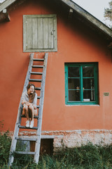 woman in front of brick wall on a ladder
