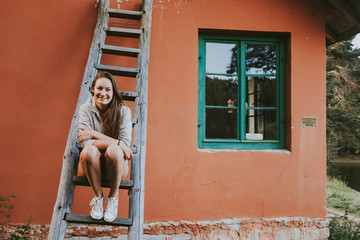 woman in front of brick wall on a ladder