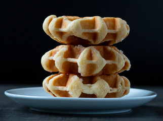 three large waffles on a plate on a wooden table