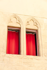 Montpellier, France. Two windows with decorations and red curtains