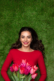 Happy woman with tulips lying on meadow 