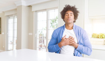 African American man at home smiling with hands on chest with closed eyes and grateful gesture on face. Health concept.