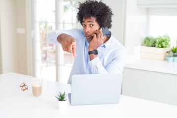 African American business man talking on the phone pointing with finger to the camera and to you, hand sign, positive and confident gesture from the front