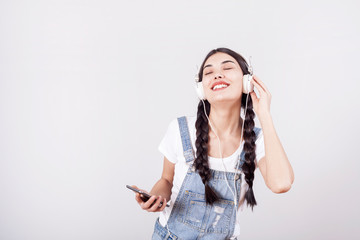 Young girl portrait of listening music on gray background
