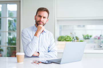 Handsome man working using computer laptop and drinking a cup of coffee serious face thinking about question, very confused idea