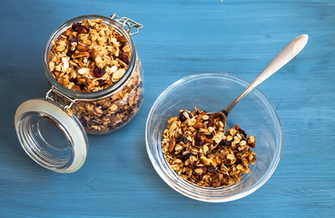 Homemade muesli in a plate on a blue background, healthy breakfast of oatmeal muesli, nuts, seeds and dried fruits
