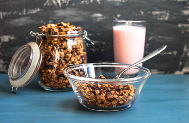 Obraz na płótnie Canvas Homemade muesli with yogurt in a plate on a blue background, healthy breakfast of oatmeal muesli, nuts, seeds and dried fruits