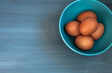 top view of eggs in a blue bowl on a blue wooden background. copy space