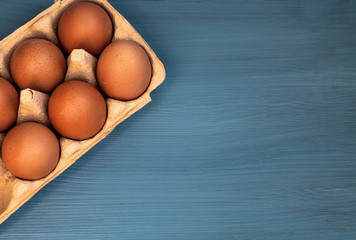 top view of eggs in a box on a blue wooden background. copy space