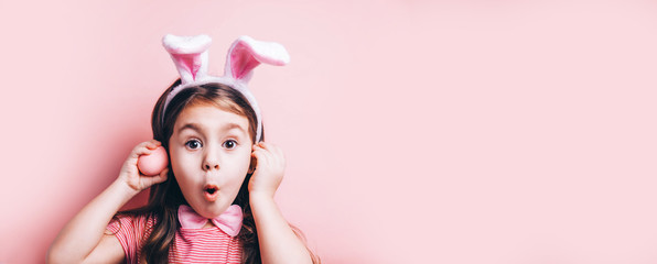 Obraz na płótnie Canvas Cute little girl with bunny ears on pink background.