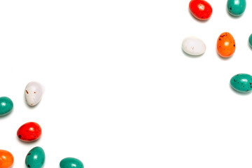 Easter frame made from colorful eggs and big chocolate egg flat lay on white background. Top view, copyspace for text.