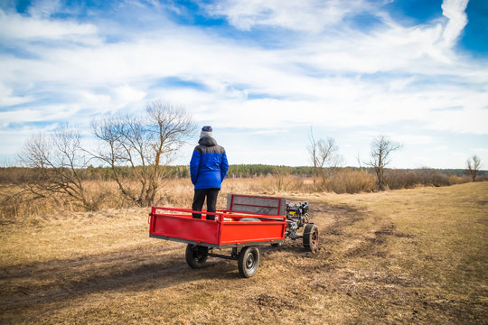 A man on a motoblock rides a field road in spring in March