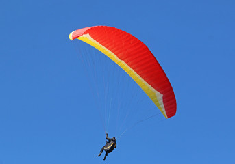 Paraglider flying red and yellow wing