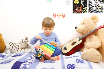 Ein dreijähriger Junge spielt auf einem Holzxylophon