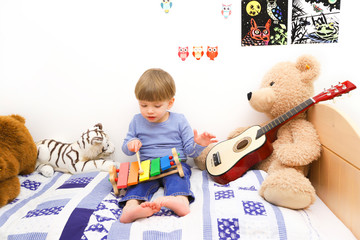 Ein dreijähriger Junge spielt auf einem Holzxylophon
