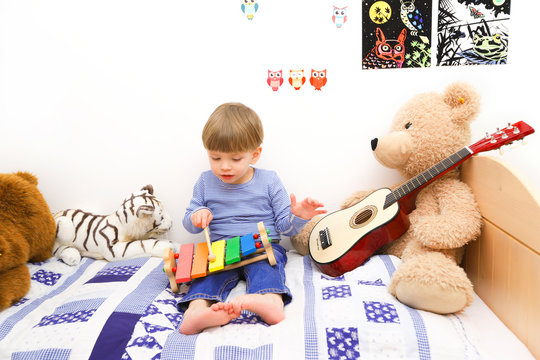 Ein dreij&auml;hriger Junge spielt auf einem Holzxylophon
