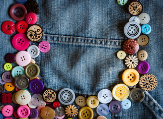 sewing buttons on denim jeans background