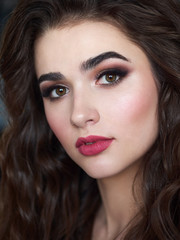 Fototapeta premium Portrait of beautiful elegant woman with brown curly hair, trendy styling, beautiful makeup, glossy, smooth skin posing for makeup artist social network portfolio