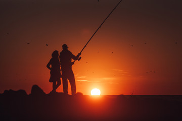 Fototapeta na wymiar Couple fishing during beautiful and warm sunset