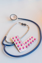 Stethoscope with pile of  antibiotic capsule pills on table with drug tray. Antimicrobial drug resistance and overuse. Medical equipment for doctor. healthcare. Pharmaceuticals.healthy lifestyle