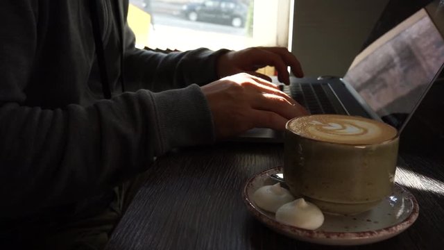 Digital technology, software development concept. Close-up hands - software developer (programmer) typing code for mobile device. Business office concept with cup of coffee and wooden table. Freelance
