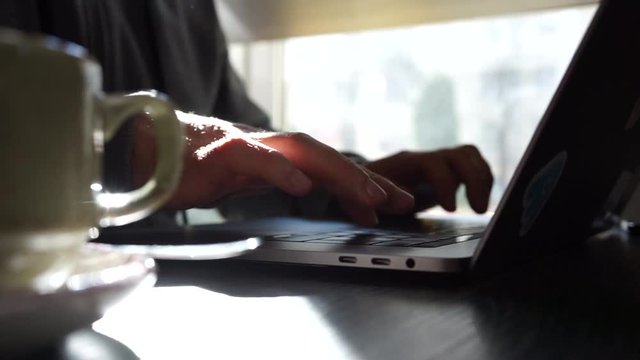 Digital technology, software development concept. Close-up hands - software developer (programmer) typing code for mobile device. Business office concept with cup of coffee and wooden table. Freelance