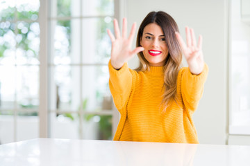 Young beautiful woman wearing winter sweater at home showing and pointing up with fingers number nine while smiling confident and happy.