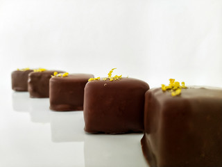 Chocolate candies in the form of cubes, decorated with zest on a white background close-up