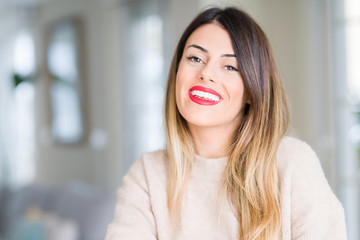 Young beautiful woman wearing winter sweater at home happy face smiling with crossed arms looking at the camera. Positive person.