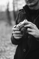 man holding an old analog camera on a forest walk