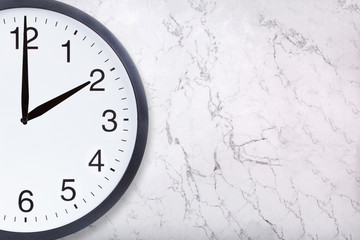 Closeup of wall clock show two o'clock on white marble texture. Office clock show 2pm or 2am on marble background. Crop image