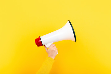 megaphone in hand on a yellow background, attention concept announcement - obrazy, fototapety, plakaty