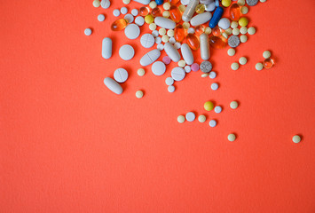 Assorted pharmaceutical medicine pills, tablets and capsules and bottle on red background. Drugs and various narcotic substances. Copy space for text. Stock photo for design