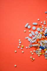 Assorted pharmaceutical medicine pills, tablets and capsules and bottle on red background. Drugs...