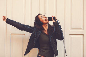Young woman enjoys music on the street and dancing