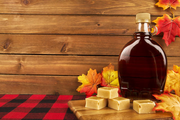 Maple syrup bottle on a wooden plank. Maple leaves in decoration. Copy space for your text. - 254753795