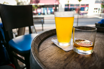 Ice cold pint of beer and whiskey neat in a glass, on an oak barrel table at a city neighborhood restaurant/pub. 