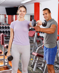 Instructor helping woman with dumbbells