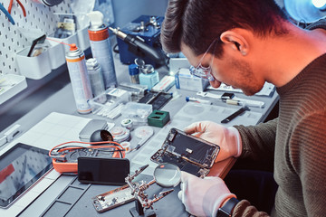 The technician carefully examines the integrity of the internal elements of the smartphone in a...